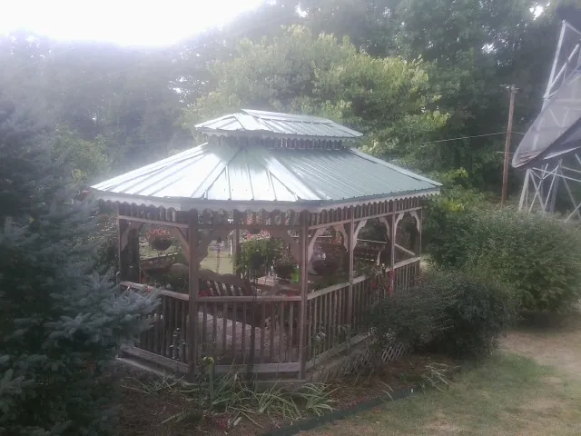 Green metal roof on a backyard gazebo surrounded by garden beds in Oakland