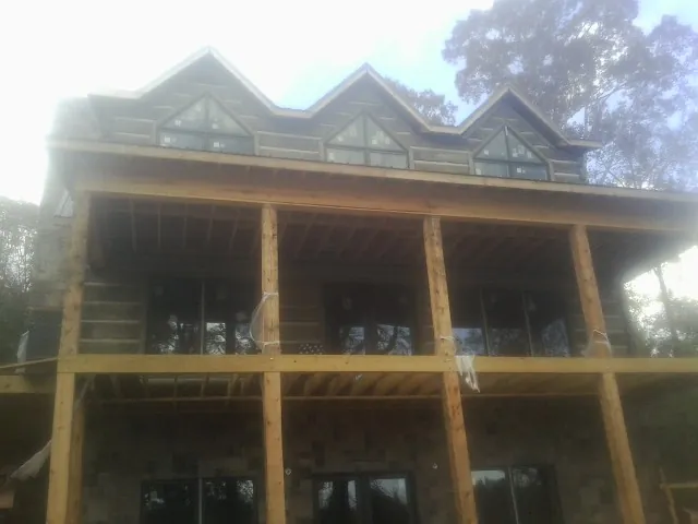 Dormers and porch framing on a large log home under construction — Roof Coating work by our crew in Oakland