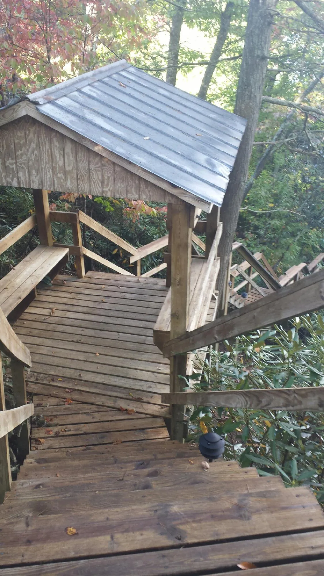 Metal roofed shelter over wooden steps on a wooded walkway — Skylight Repair & Installation work by our crew in Oakland